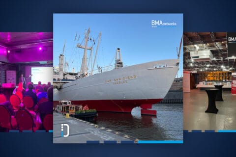 Segelschiff Cap San Diego mit weißem Rumpf und rotem Unterwasseranstrich im Hafen von Hamburg, blauer Himmel, Logo BMA networks oben rechts sichtbar.
