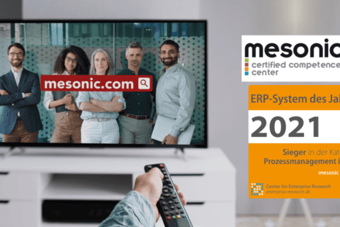 Fernseher zeigt fünf Personen vor einer Suchleiste mit Text „mesonic.com“. Rechts daneben Auszeichnung „mesonic certified competence center“ mit Text „ERP-System des Jahres 2021, Sieger in der Kategorie Prozessmanagement in ERP, mesonic WinLine“. Hand mit Fernbedienung im Vordergrund. Darstellung im Kontext von Digitalisierung und IT-Lösungen.