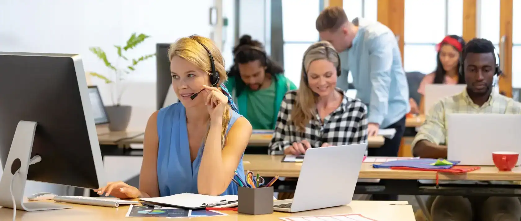 Mehrere Mitarbeitende in einem modernen Büro mit Headsets und Laptops, die Kundenservice und IT-Support leisten, symbolisieren professionelle IT-Beratung und Managed Services der dierckgroup.